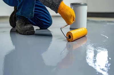 Services applying epoxy paint to a concrete floor with a roller during a renovation project photo (1)